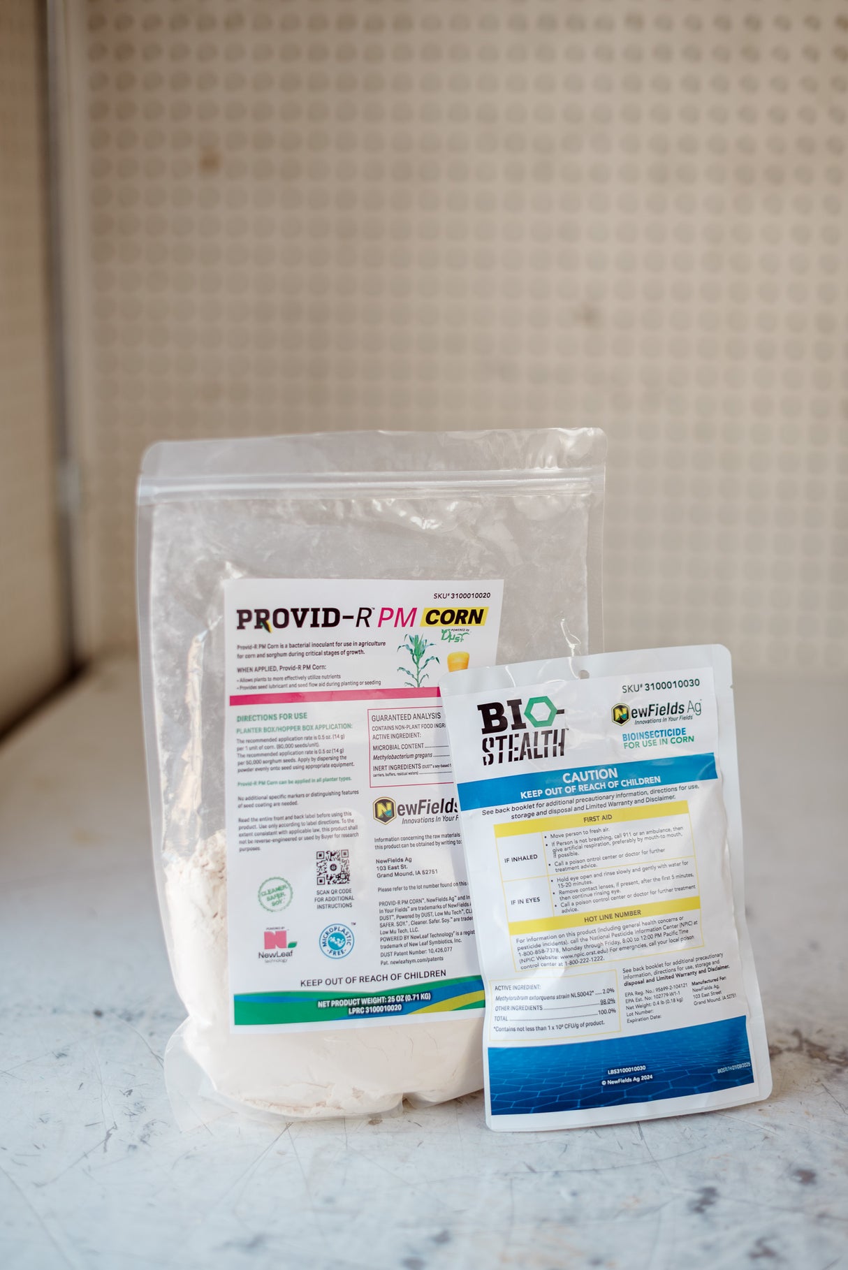 Two packages of agricultural products on a marble surface with a neutral background