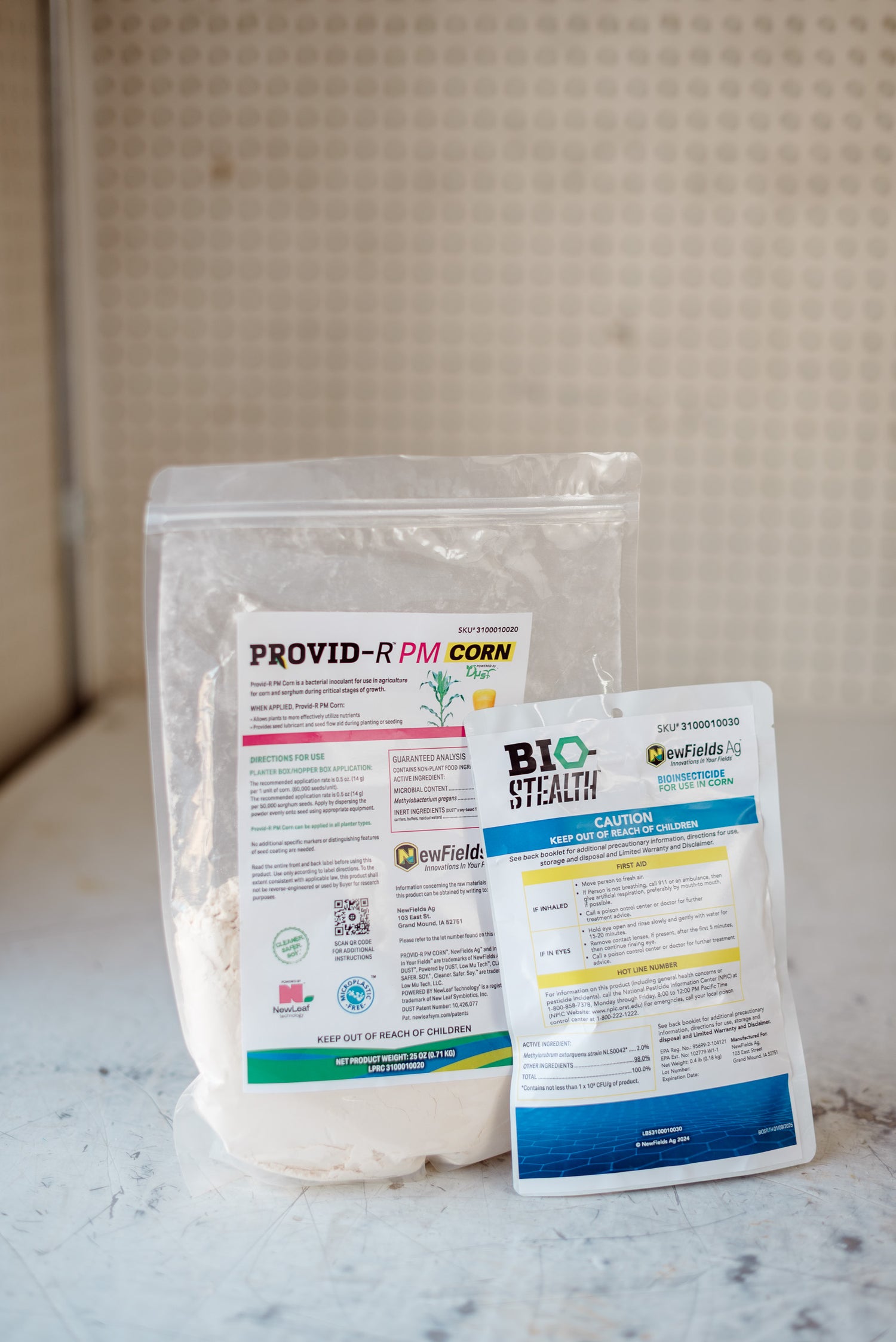 Two packages of agricultural products on a marble surface with a neutral background